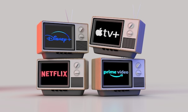 Four old-style television sets are stacked in two rows and each screen displays a different streaming service logo: Disney+, Apple TV+, Netflix, and Prime Video.