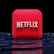 A red, cube-shaped icon with the word 'NETFLIX' prominently displayed in white, bold letters. The cube is set against a dark, glossy, circular patterned background, reflecting a sleek, futuristic design.